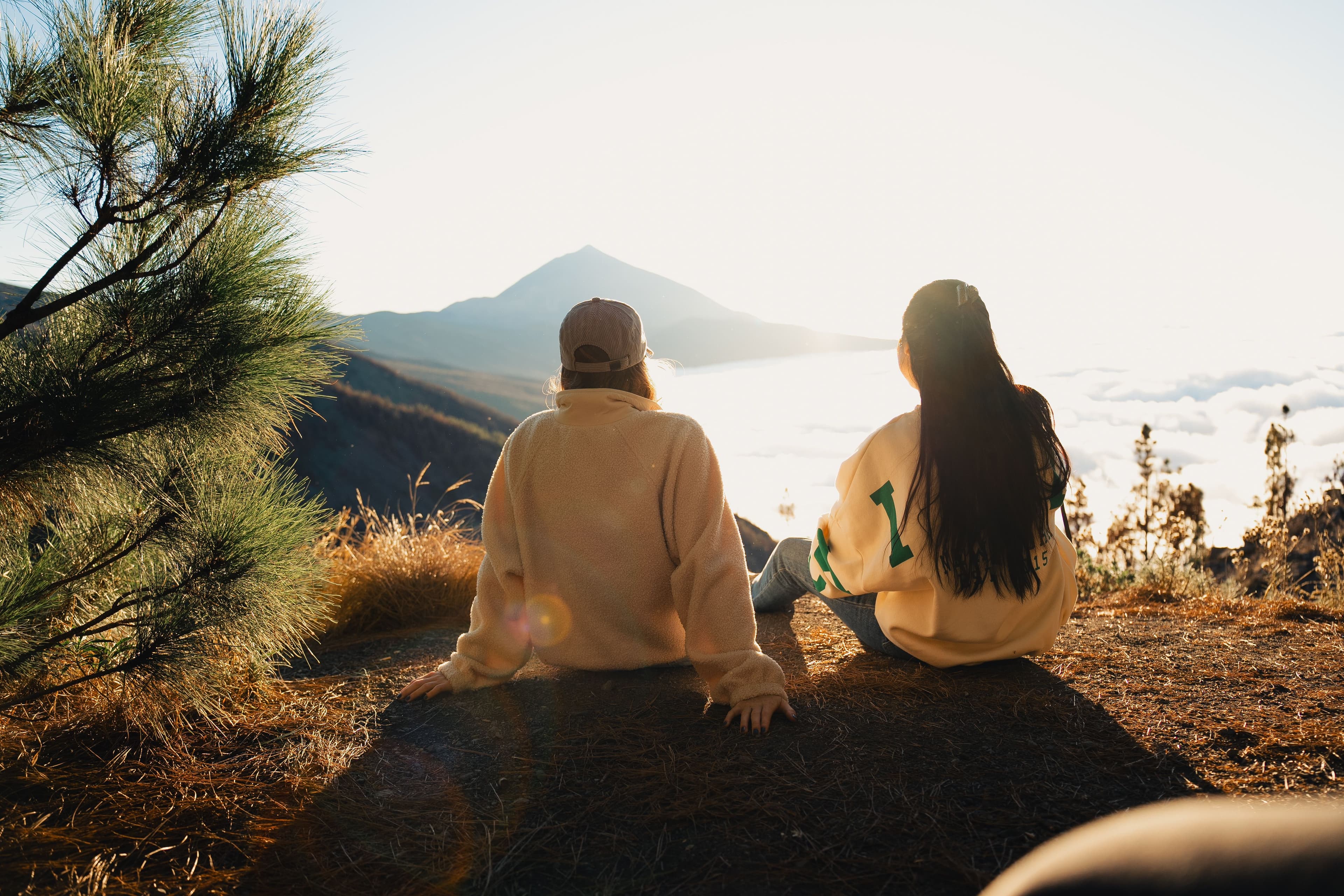 Women sitting on hilltop with clouds below